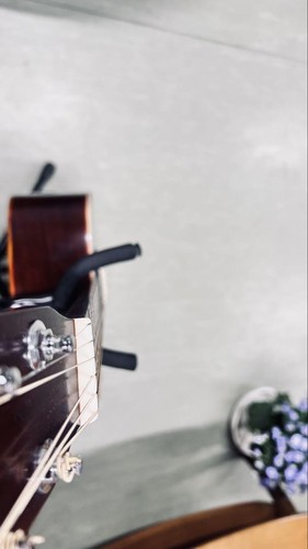 Acoustic guitar with silver hardware and rosewood fretboard, S/N 375511, on light gray wall with black strap.