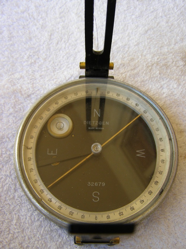 A brass-bodied Dietzgen pocket transit compass in its original leather case — a century-old surveying instrument that looks like a prop from an Indiana Jones film and actually works.