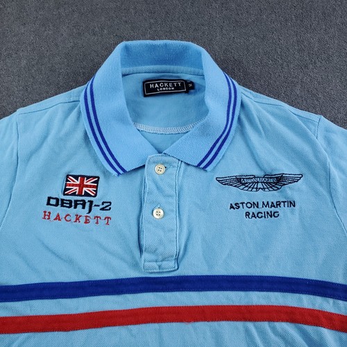 Light blue Hackett London polo shirt with navy trim, embroidered Aston Martin Racing logo, and Union Jack on left chest.