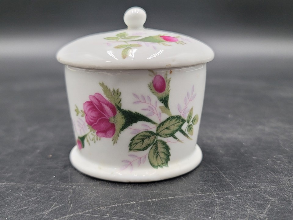 A charming vintage ceramic stamp-roll holder with floral decoration — a petite, practical relic from the days when snail mail was king.