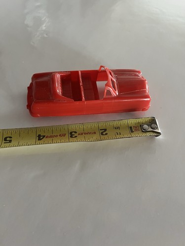 Red vintage 1950s BHS plastic convertible car with black interior, shown beside a yellow measuring tape for scale.