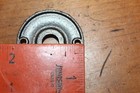 Round black cast iron doorknob escutcheons with ornate cutout bow design, positioned beside red tape measure.