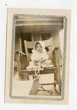 Cute Baby Wearing a Bonnet Sitting in a Rocking Chair Black and White Photo