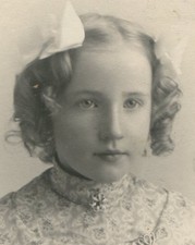 YOUNG GIRL WITH BOWS IN HER PIGTAILS, LOCKET OVER HER HEART. MCKEESPORT, PA.