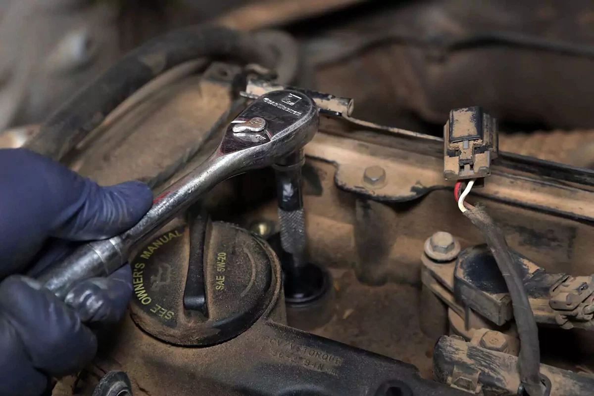 Ratchet being used to tighten a new spark plug.