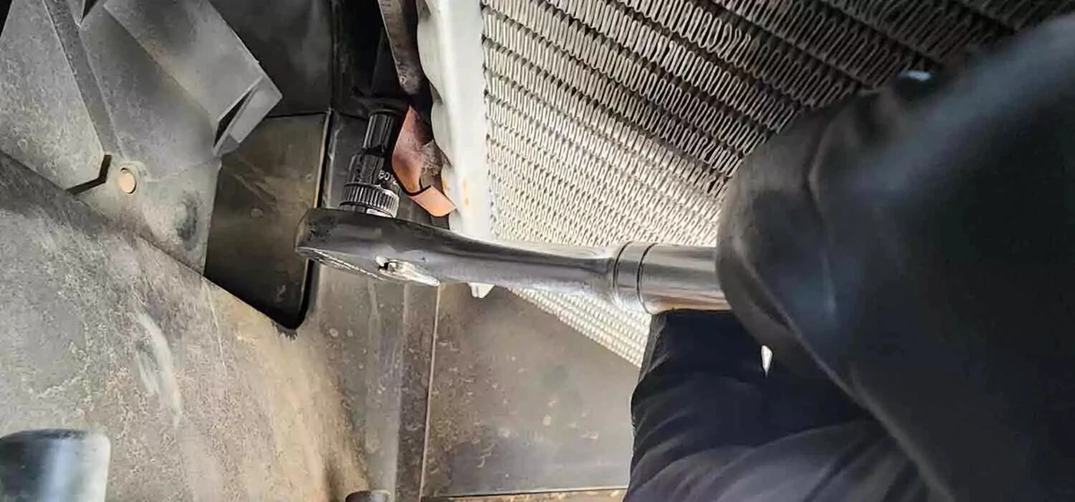 A mechanic uses a ratchet to remove the bolt from a heater core.