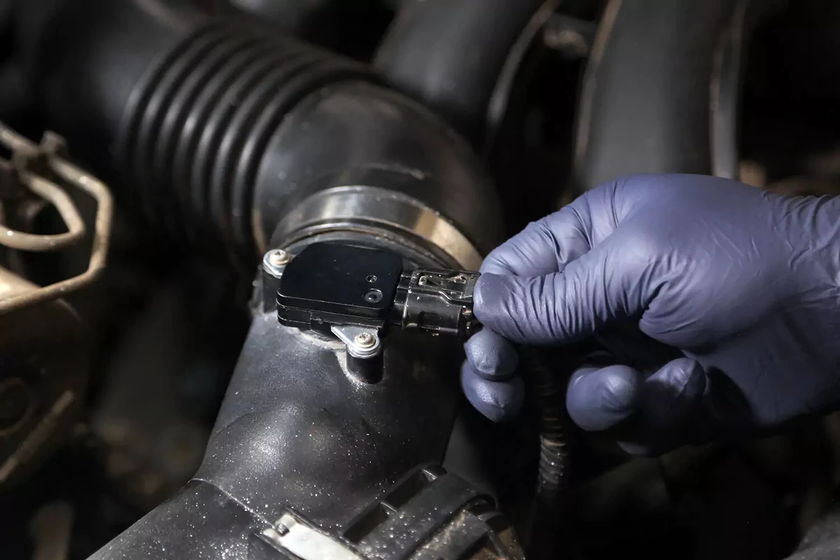 A mechanic connecting a wiring harness to an MAF sensor.