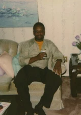 Man Sitting Couch Drink in Hand Candid Portrait Flowers Lamp Polaroid