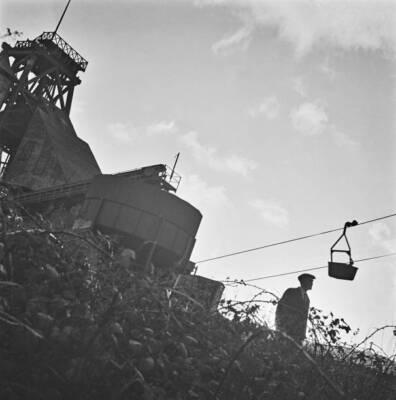 Mine worker looks up aerial ropeway transporting tin ore pit he- 1942 Old Photo