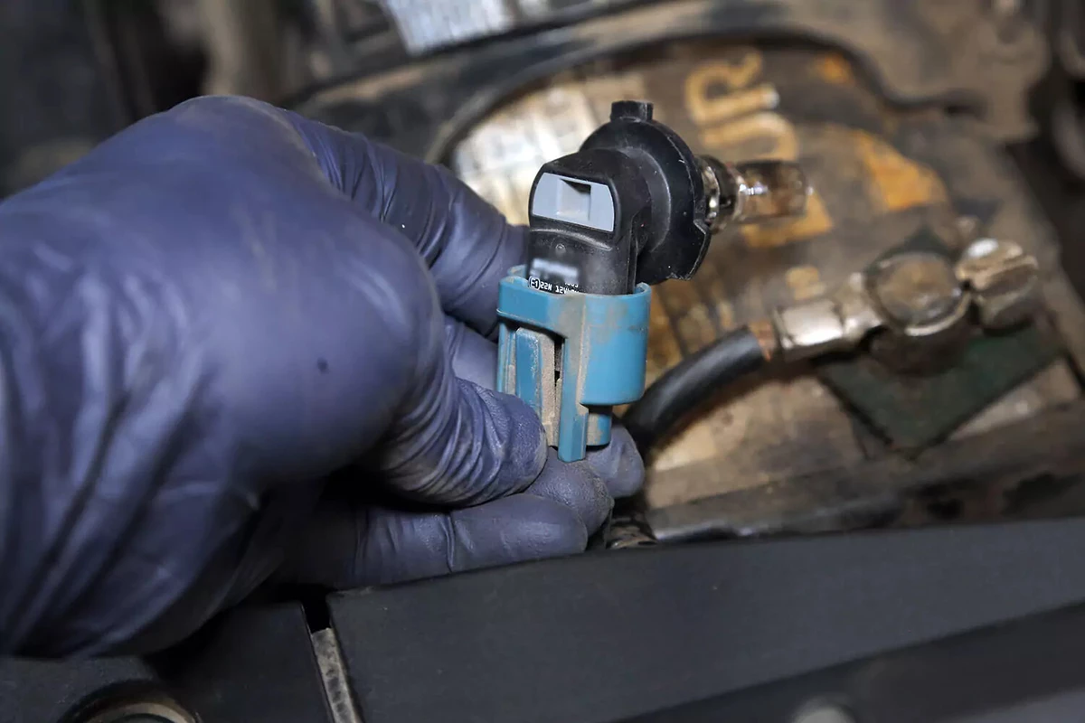 Removing a headlight bulb to be able to install a new headlight bulb.