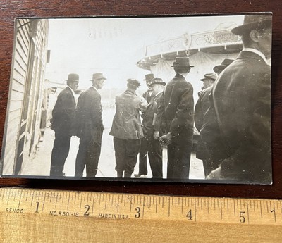 RPPC, Men in Hats standing next to Carousel which is closed. Flag is above them.