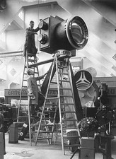 Two men wooden ladders erecting a giant camera a tall tripod a- 1930s Old Photo
