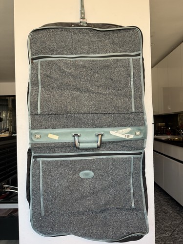 vintage tweed-patterned garment bag with light blue trim and a central oval.