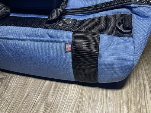 Blue Club Glove golf bag with black carry strap, side pocket, and small red flag featuring white stitching.