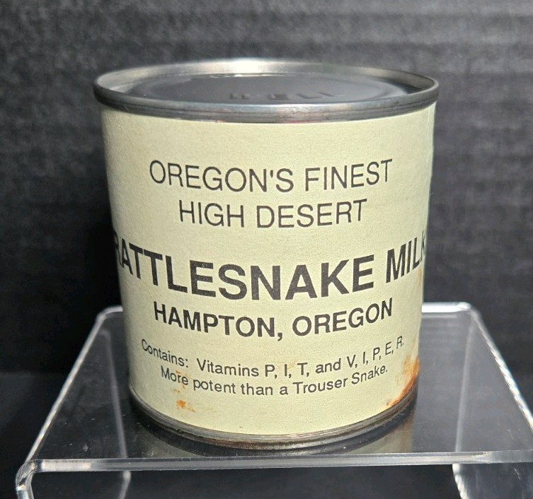 A 1990 tin can of 'Rattlesnake Milk — Oregon's Finest' is peak roadside-America absurdity and still sealed for maximum shelf credibility.