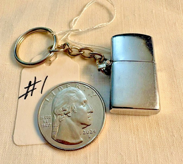A slick silver-tone mini fluid lighter that doubles as a keychain — the kind of tiny retro object that sparks conversation the moment someone spots it on your keys.