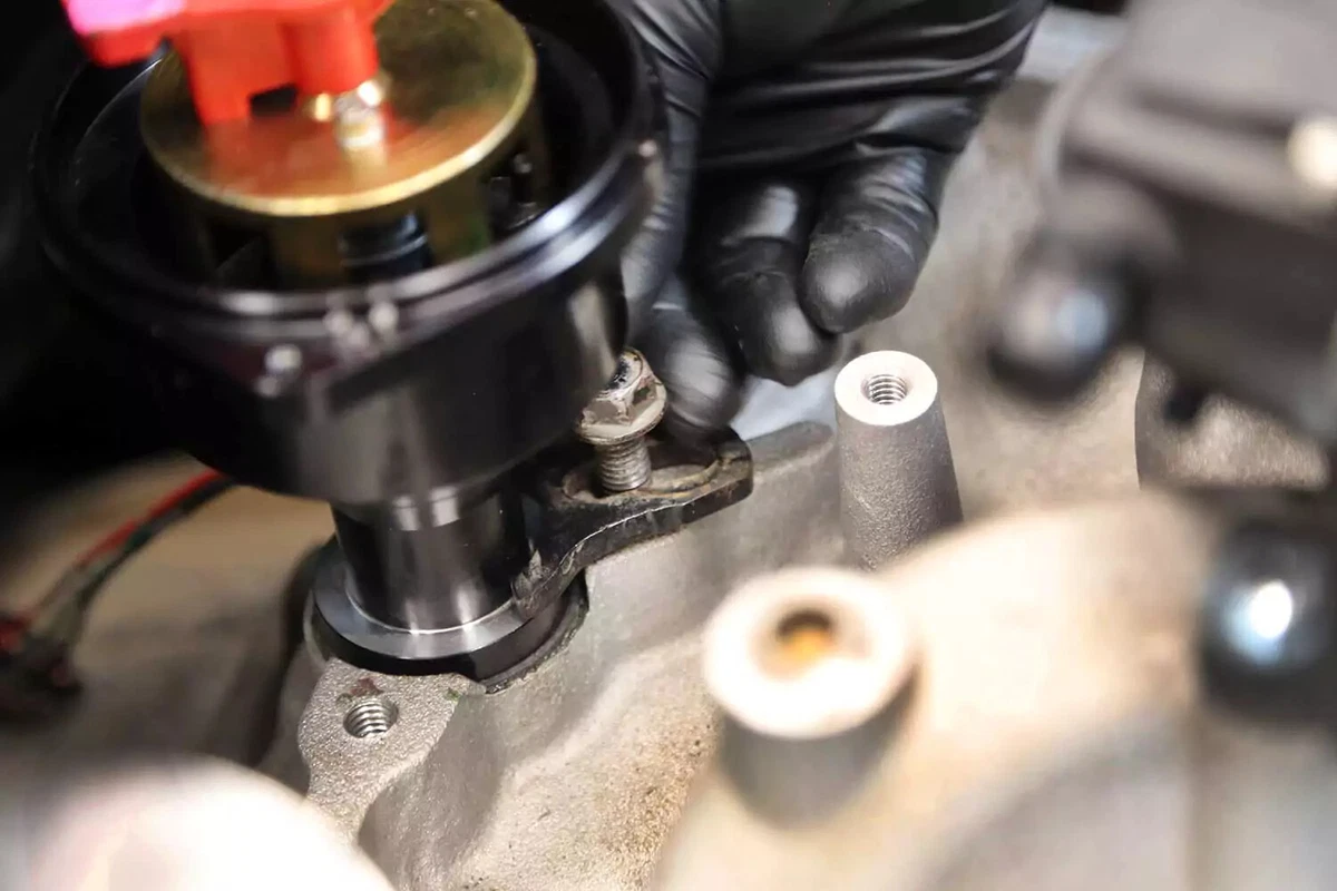 A mechanic threads the distributor lockdown bolt by hand.