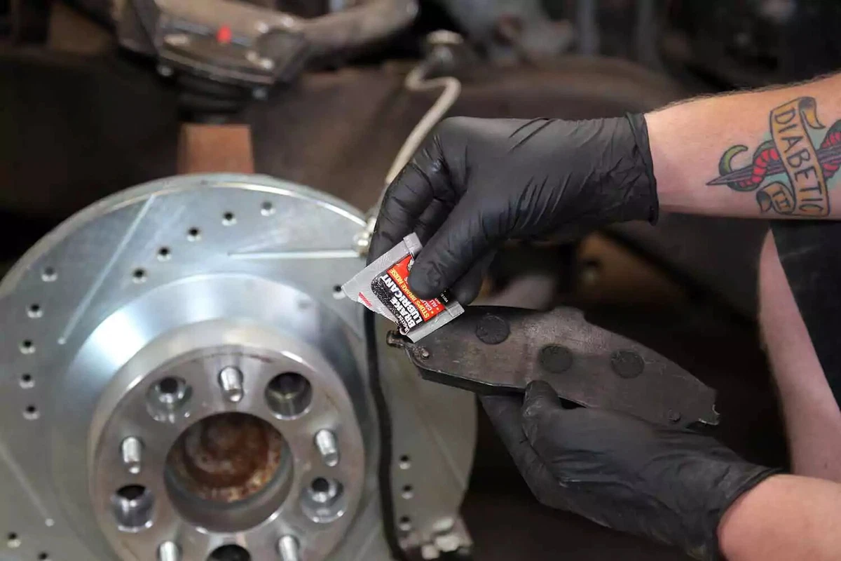 A mechanic adding a dab of brake grease to the end of a brake pad.