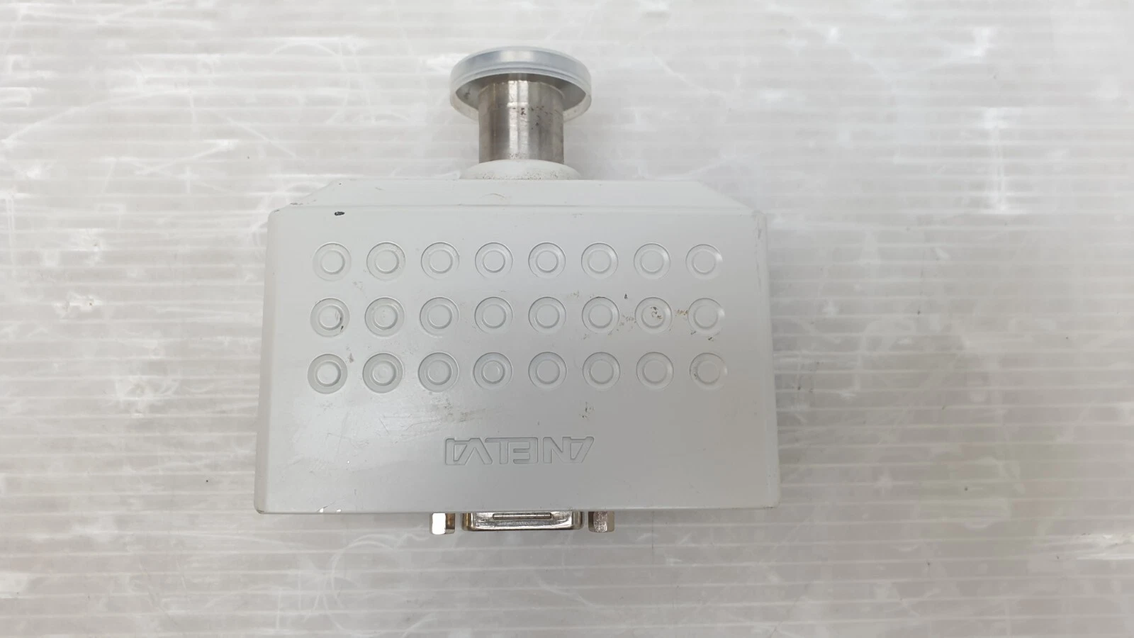 Top of the Anelva M-320XG crystal gauge housing with ventilation pattern and KF flange
