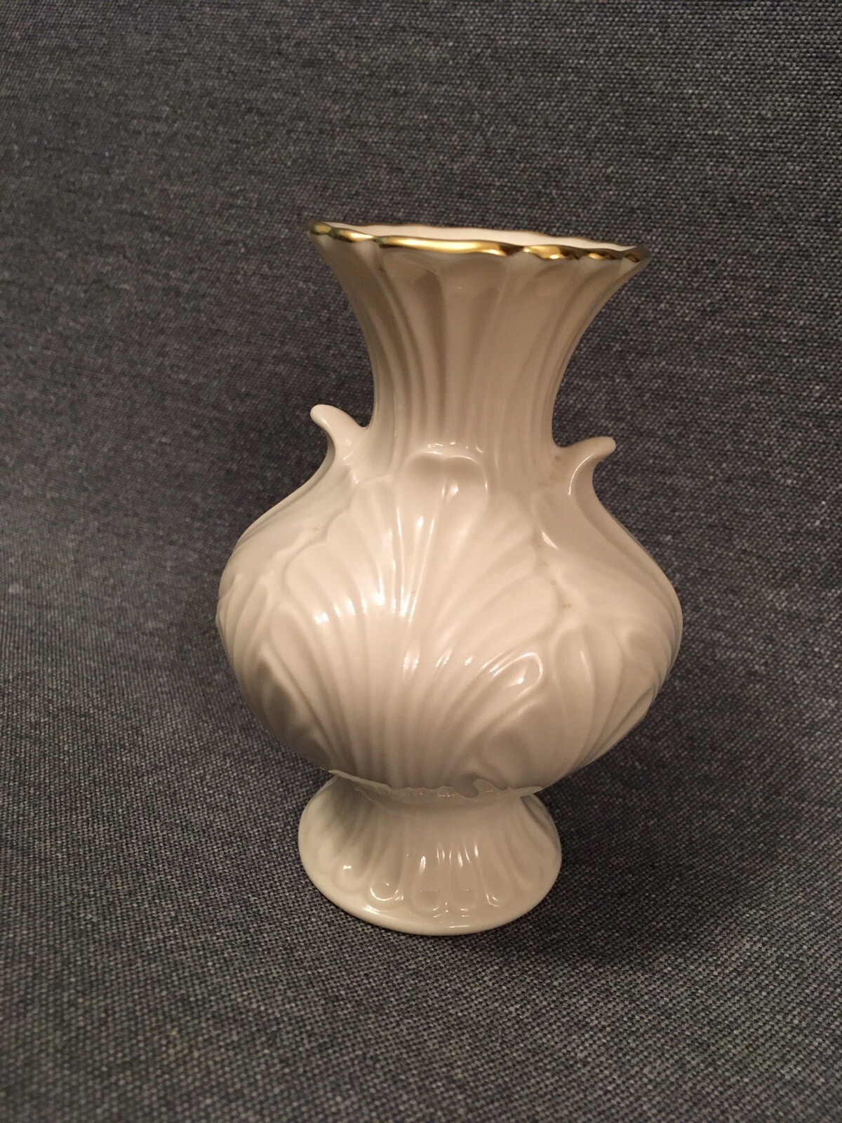 Cream Made in the USA 24K Lenox vase with fluted fan shape and gold rim on dark background.