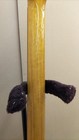 Yellow electric guitar neck with visible scratches and textured surface, black tuning pegs, and purple fabric grips.