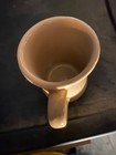Beige ceramic mug with a tapered handle, white interior, and “Tepco Made in U.S.A.” logo on a dark background.