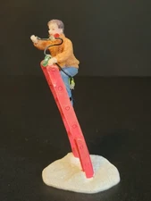 St. Nicholas Square Christmas Village Man Putting Up Lights On Red Ladder