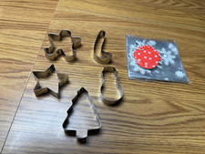 Five Christmas themed cookie cutters with a package of cookie bags