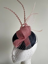 Navy fascinator with round base and pink loops, netting and feathers.