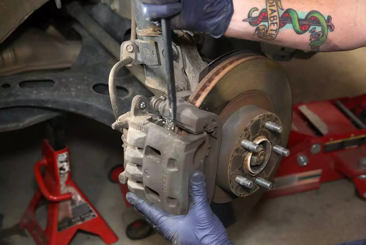 Lifting a brake caliper off the rotor with a pry bar.