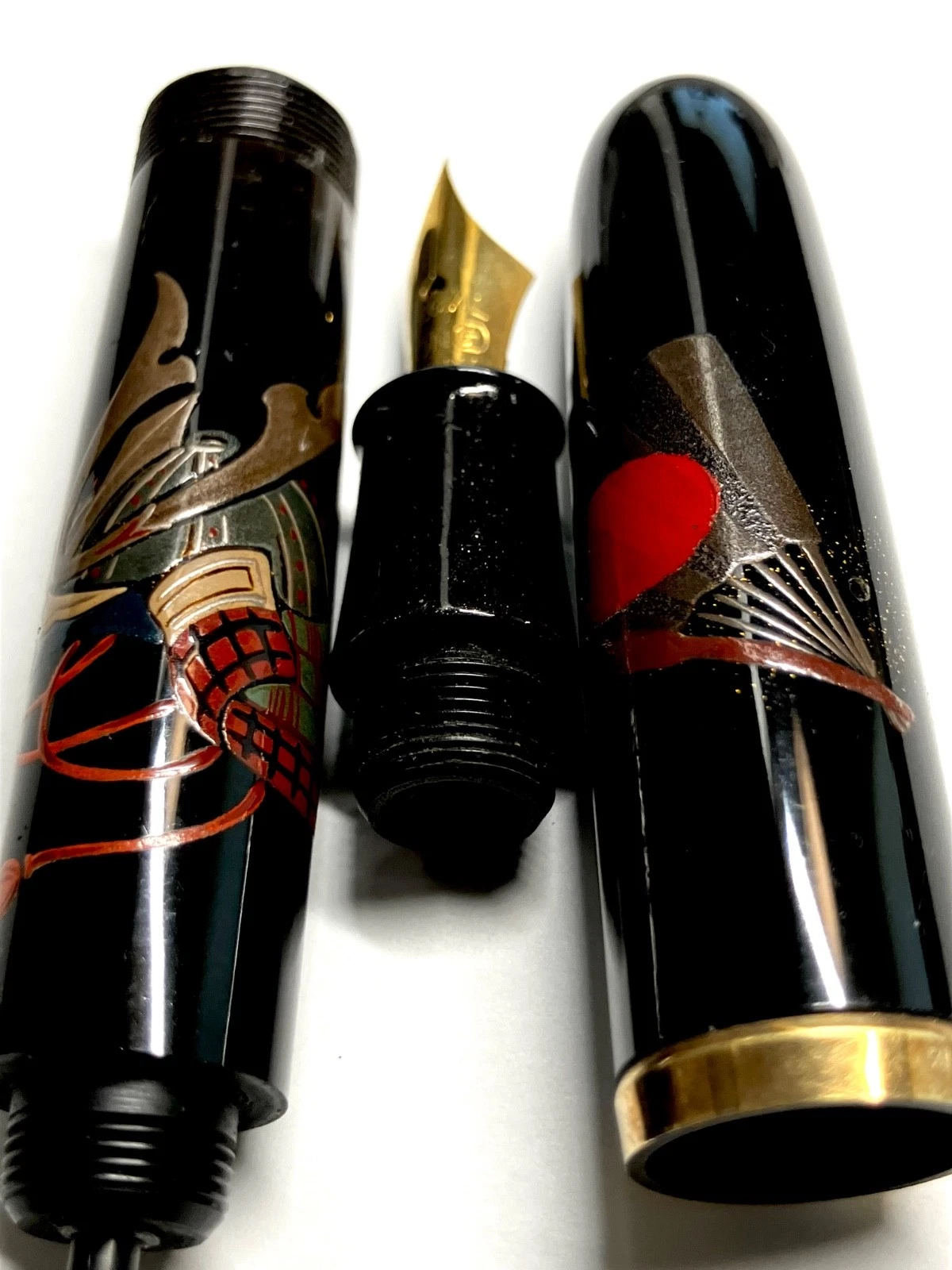 Black ink shut off fountain pen with gold tip, red and green dragon design, and detached black body with gold band.