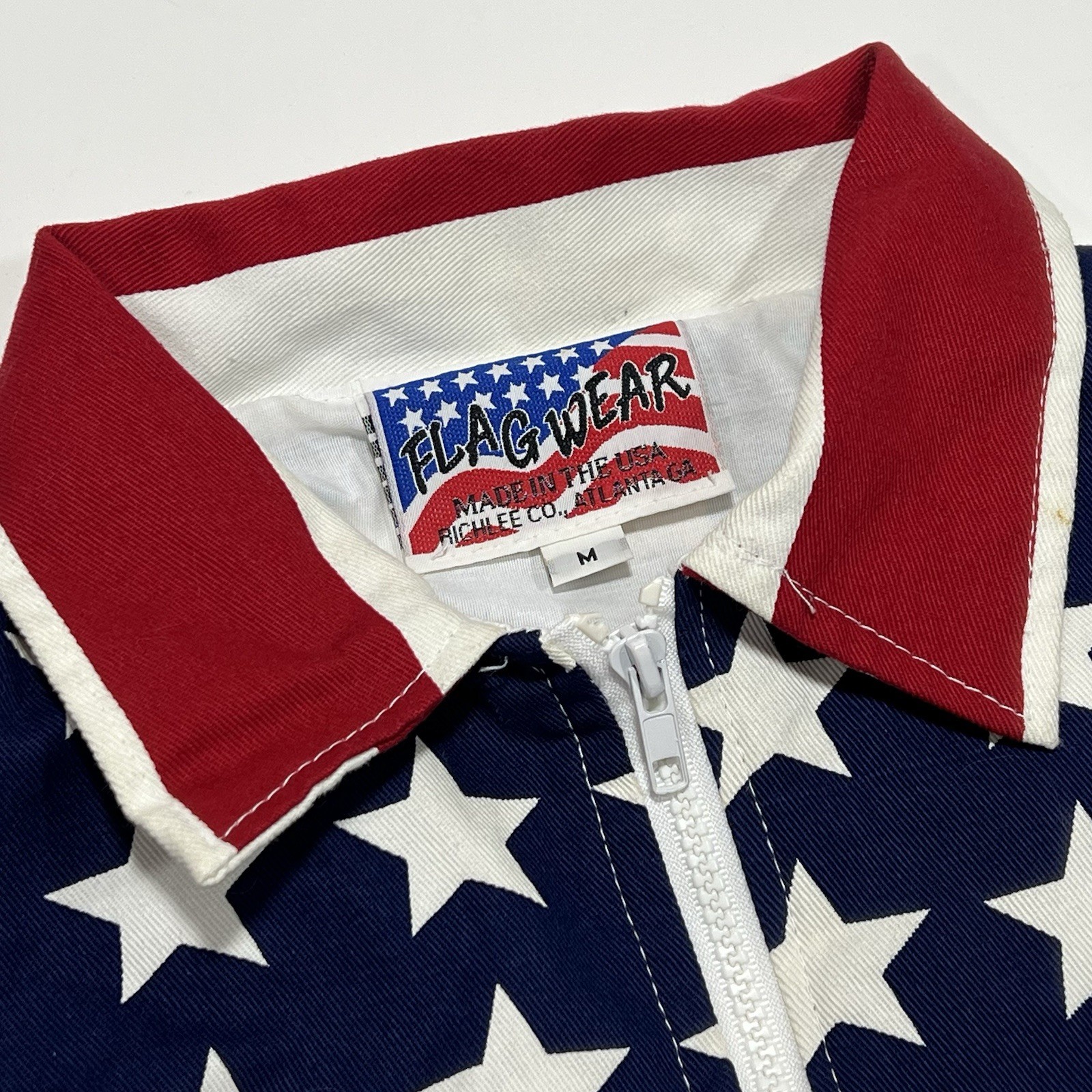 White vintage Flag Wear jacket with red and blue stars and “Made in U.S.A.” label on collar.