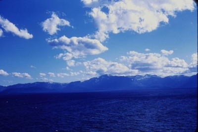 RED BORDER SLIDE Deep blue lake, snow-capped mountains, cloudy blue sky.