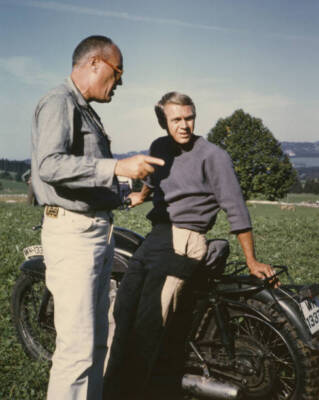 Steve McQueen leaning on motorbike with director John Sturges duri- Old Photo