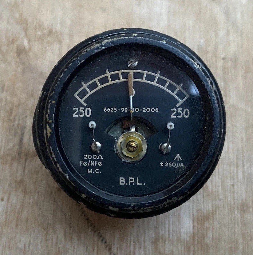 A genuine Cold War-era BPL moving coil microampere meter with NATO stock number — a beautiful piece of scientific instrument history that doubles as industrial-chic desk art.