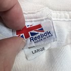 White fabric tag on collar of vintage Reebok Runners t shirt with blue, red, and yellow text reading “Made in USA Large.”