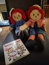 Vintage handmade Raggedy Ann and Andy dolls with their book.