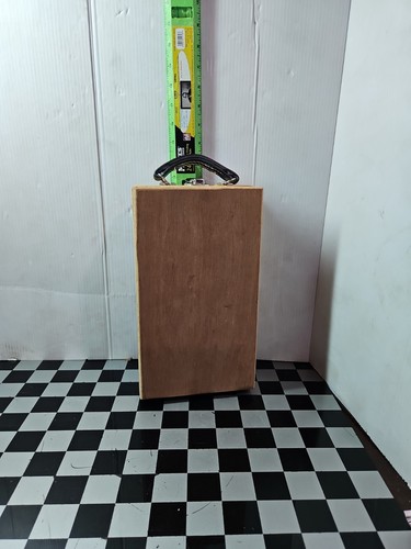 Rectangular wooden base with black metal handle, 11 chisels, and green oilstone box on tiled floor.