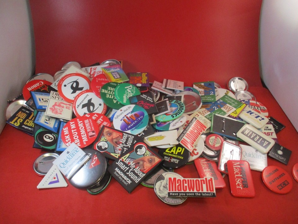 A massive haul of vintage MacWorld and PC/DOS convention enamel pins — a treasure trove for the retro computing collector who wants wearable computing history.