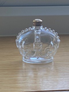 A crown shaped glass perfume bottle with a gold coloured screw top
