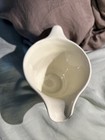 Cream ceramic bowl with subtle swirl pattern, long handle, and “Made in U.S.A.” floral print on the side.