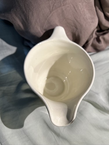 Cream ceramic bowl with subtle swirl pattern, long handle, and “Made in U.S.A.” floral print on the side.
