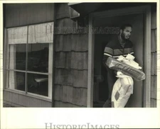 1984 Press Photo Sam King Exits Check-In Office Carrying Bedding - nob48549