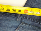 Yellow measuring tape with black vertical scale marked 28X31, placed on blue denim jeans with five-pocket design.