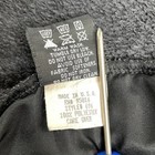 White fabric tag on black straight down vest, dark gray Polartec fleece, with iron, wash, and care instructions.