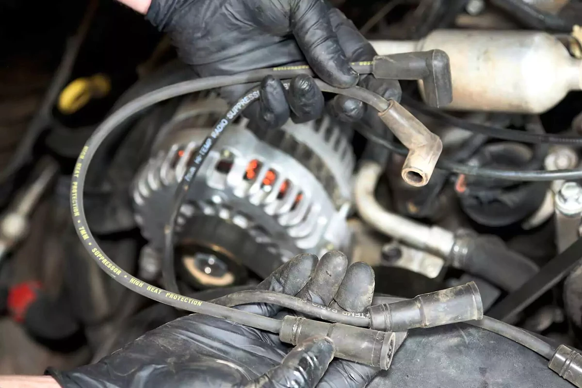 A mechanic holds two spark plug wires of differing lengths.