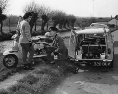 An AA patrol man helping a woman whose scooter had broken down Old Photo