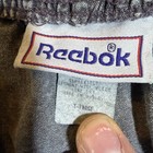 Gray vintage Reebok Riptop Shorts, men's XL, with white printed neck label, red “Reebok” logo, and blue distressed stitching.