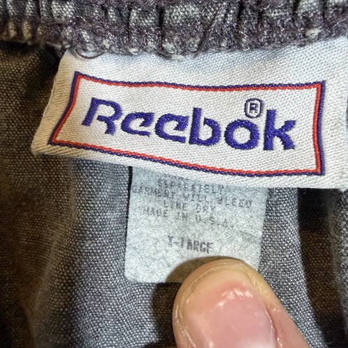 Gray vintage Reebok Riptop Shorts, men's XL, with white printed neck label, red “Reebok” logo, and blue distressed stitching.