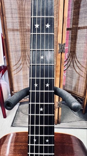 Black Martin D-76 limited edition guitar with silver hardware, six stars, and white butterflies, displayed on padded stand.